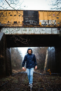 Man walking on railroad track against bridge