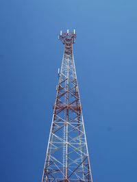 Low angle view of communications tower against clear blue sky