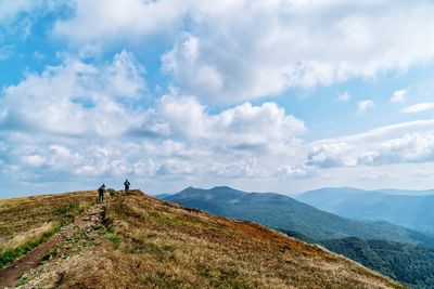 People standing on mountain against sky