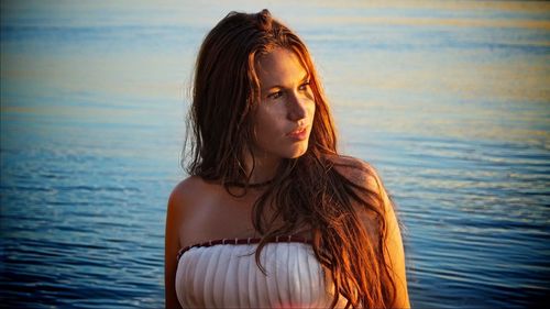 Portrait of beautiful young woman standing against sea