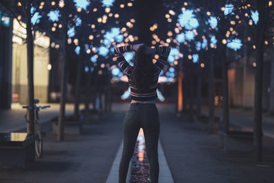 Rear view of woman standing in city at night
