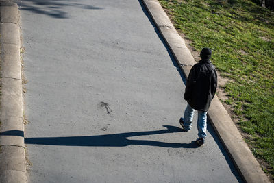 Rear view of man walking on footpath