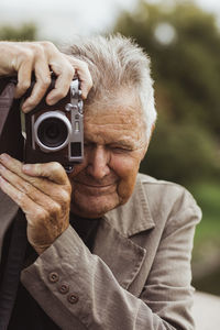 Elderly man photographing through camera during vacation