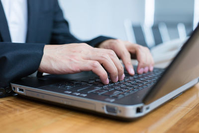 Midsection of man using laptop on table