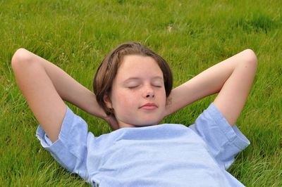 Teenage girl sleeping on grassy field