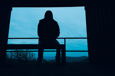 Silhouette of man sitting against sky