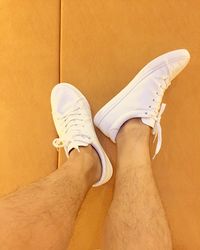 Low section of man wearing white canvas shoes sitting on floor