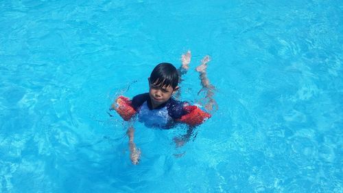 High angle view of boy wearing water wings swimming in pool