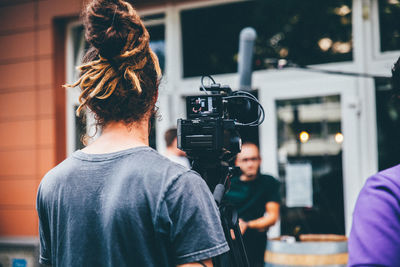 Young man with video camera by tree trunk