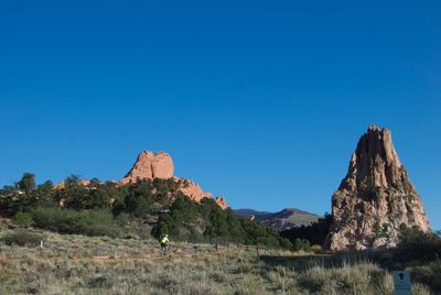 Distant man on bicycle towards majestic rock formations