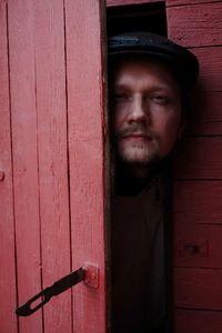 Portrait of young man standing against door