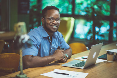 Portrait of businessman using laptop on table