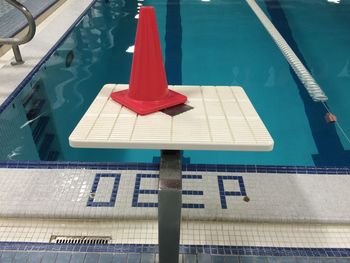 Traffic cone on diving platform by swimming pool