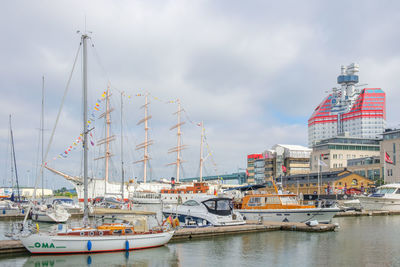 Sailboats moored at harbor in city against sky