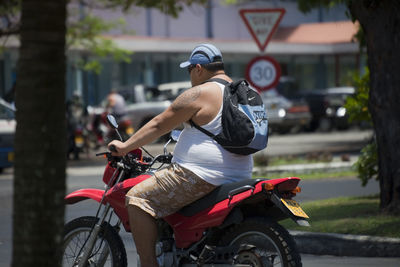 Rear view of man riding motorcycle on street