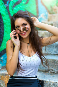 Portrait of smiling young woman wearing sunglasses on steps