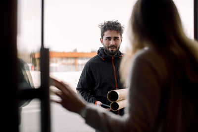 Female customer receiving package from young delivery man