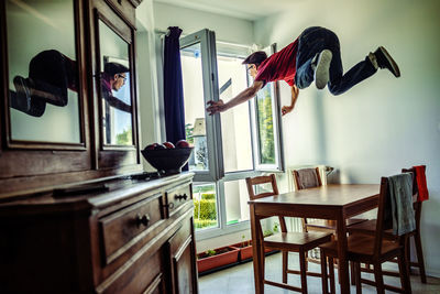 Man holding window frame while levitating at home