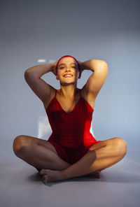 Portrait of young woman standing against black background