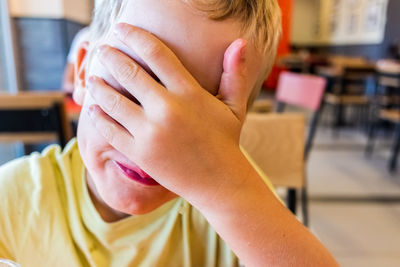 Close-up of boy with hands covering eyes