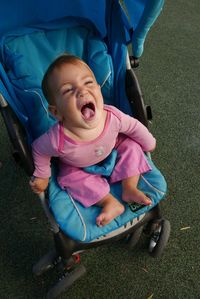 High angle view of baby shouting in stroller on field