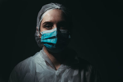 Portrait of doctor wearing mask against black background