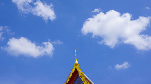 The tip of the temple roof and the beautiful cloudy sky.