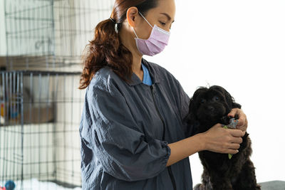 Woman grooming black dog at home