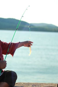 Midsection of women fishing in sea against sky