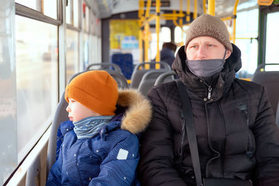 A man and a boy in a bus wearing medical masks. dad and son in a public transport. bus  during covid