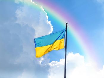 Low angle view of ukrainian flag against sky with rainbow 