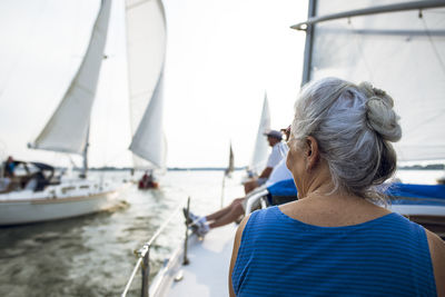 Rear view of woman on sailboat sailing in sea