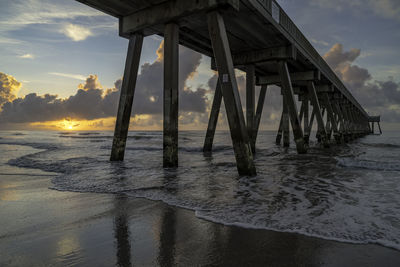 Silhouette pier on beach against sky during sunset