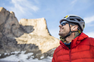 Smiling side view portrait of mountain climber below summit.