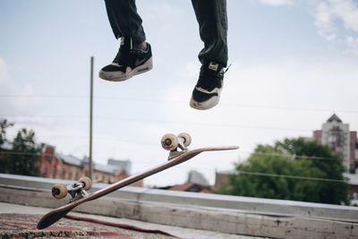 Low section of man jumping against sky