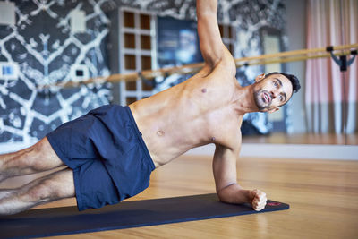 A man doing a side-plank while working out in a gym.