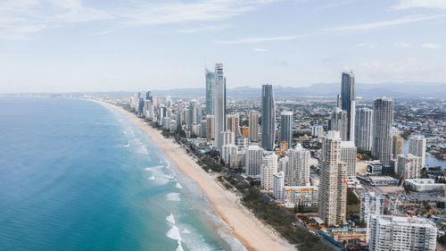 Aerial view of modern buildings by sea against sky