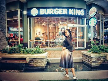 Portrait of young woman standing by store