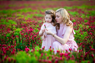 Mother and daughter amidst pink flowers