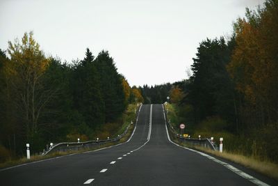 Road amidst trees against clear sky