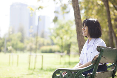Smiling woman sitting on bench in park