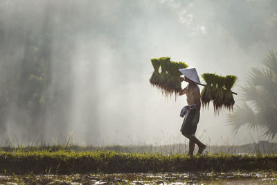 Side view of woman walking on field against sky