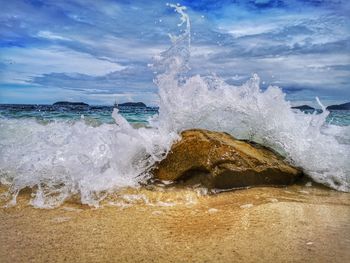 Waves splashing on shore against sky