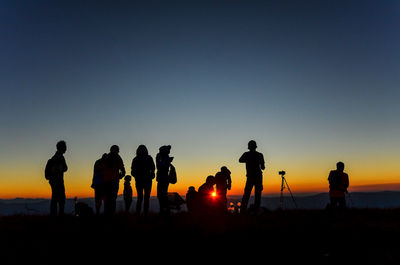 Silhouette people against clear sky during sunset