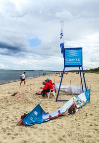 Deck chairs on beach against sky