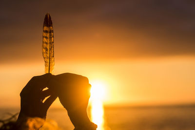 Low angle view of silhouette hand holding hands against sky during sunset