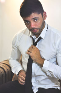 Portrait of man wearing necktie against wall