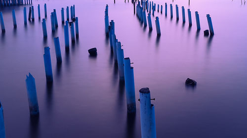Panoramic view of wooden posts in water at sunset