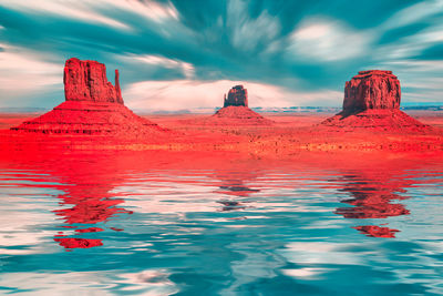 Red rock in sea against sky