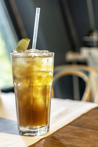 Refreshing cocktail with a straw on the table by the window in the cafe.